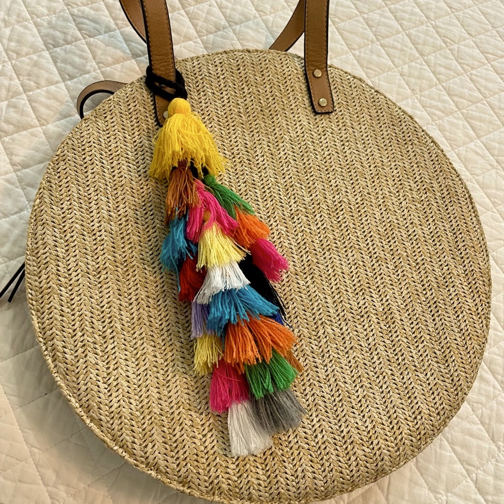 Round rattan bag with zipper close and removable tassel.